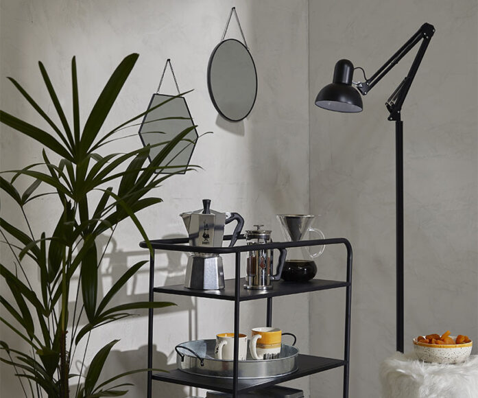 Móvel minimalista preto com várias prateleiras com itens de cozinha e decoração repousados nele 