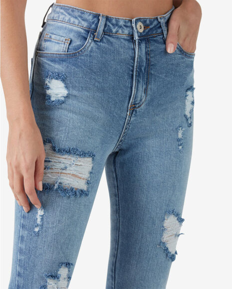 Uma calça jeans focando nos detalhes desgastados de uma calça jeans destroyed 