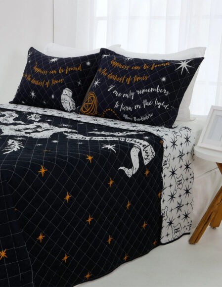 Uma cama de casal coberta com lençol preto e branco estampado do Harry Potter